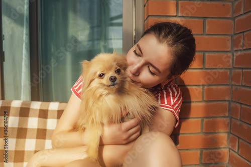Woman sitting on the floor of Balcony with spitz. Living in house with dog. Take care and love dog. Self isolation. Stay home.