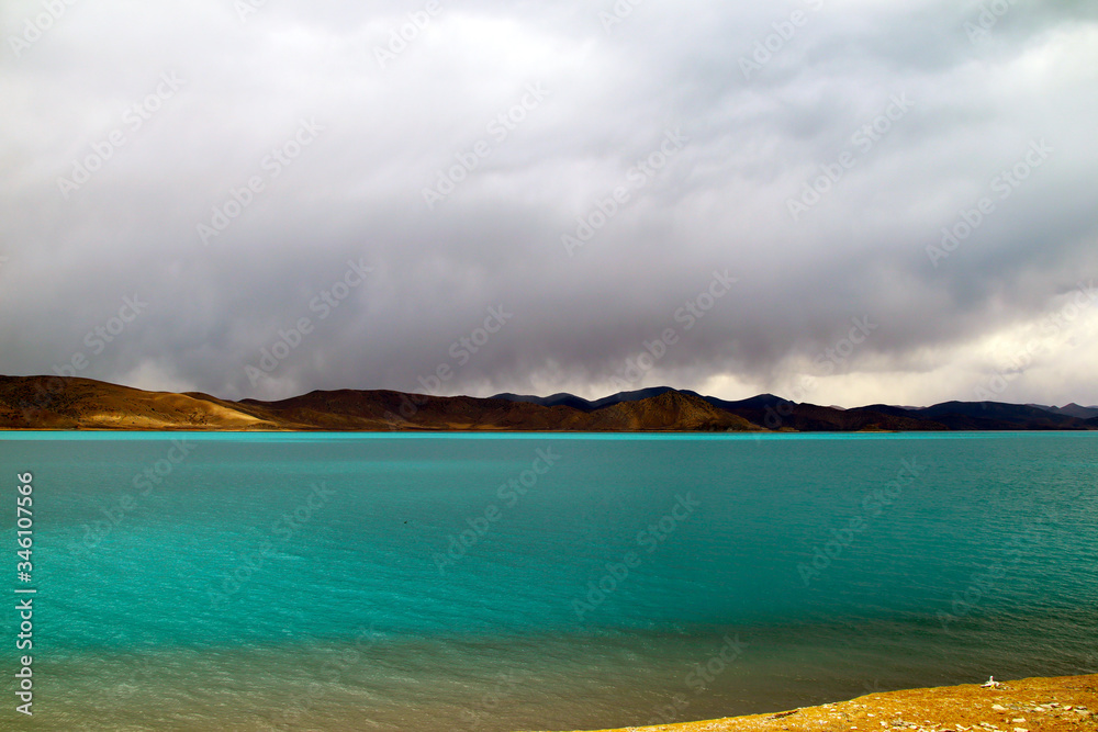 Plateau holy lake, blue-green lake water, coffee-colored distant mountains, rising water vapor and clouds