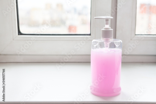 Bottle of alcohol sanitizer standing on window sill, gel for hands antibacterial cleaning and hygiene from virus, nobody