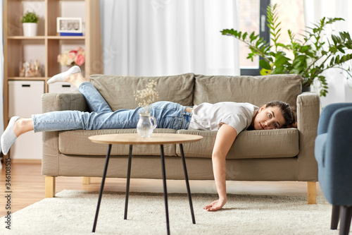 people, boredom and depression concept - bored or lazy young woman lying on sofa at home photo