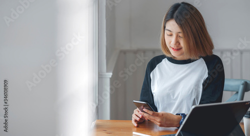 young pretty asian woman using smartphone while sitting in contemporary room.