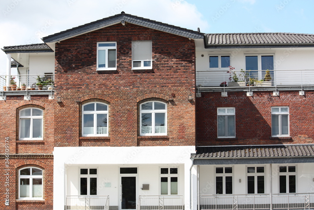 Backsteinfassade mit Fenstern und Dachterrasse