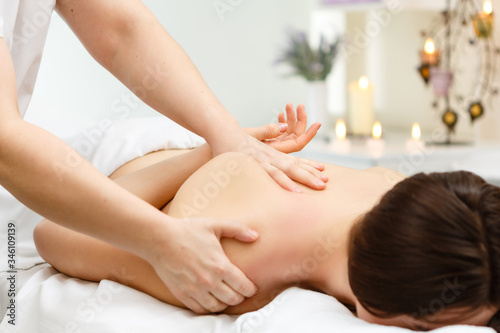 A beautiful girl lies on a massage table and she gets a massage that she enjoys in the massage room