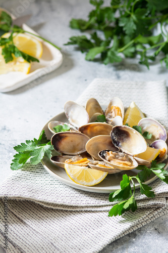 Cooked clams in a ceramic plate on a light gray table. Seafood dish