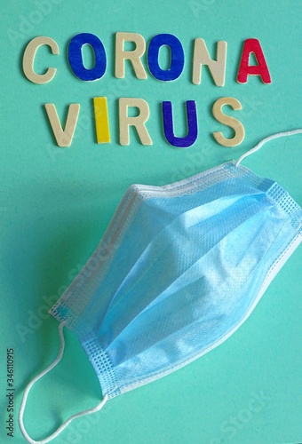 Coronavirus word written in wooden letters on a colored cardboard and a medical mask