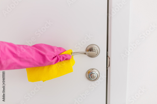 Woman hand in protective rubber gloves holding microfiber cleaning door handle, make cleaning and disinfection for good hygiene