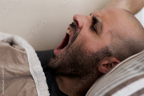 Caucasian bearded man wakes up and yawns 