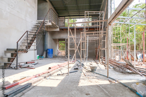 The 2 floors house under the construction has a steel ladder, scaffold and steel bar on the ground.