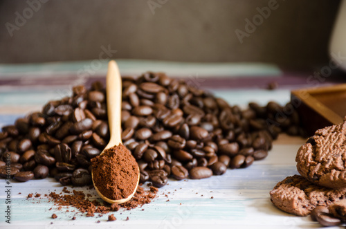 Closeup coffee beans and grinded powder on a wooden spoon