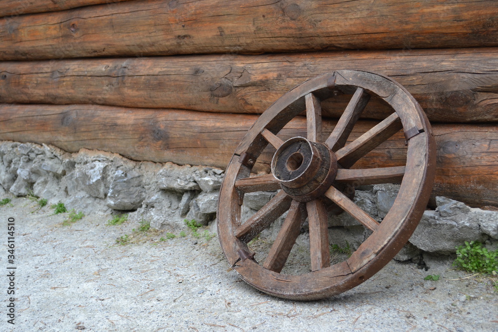  Vintage wheel from the cart on the background of a log wall