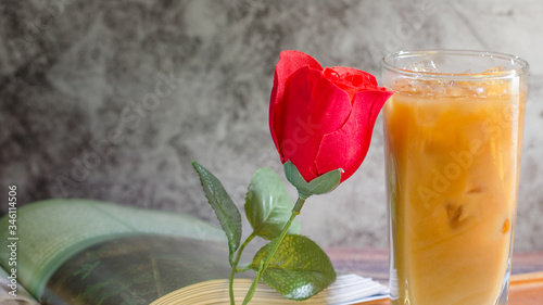Ice coffee in a tall glass with creamy mold and beautiful red rose a cool summer drink on a dark wood floor with a copying area