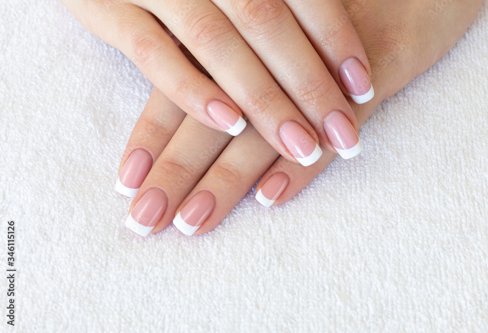 French classic manicure. Female fingers with beautiful nails on white terry towel, close up, selective focus.