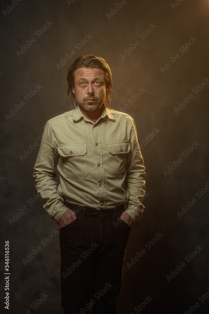 Cool fashionable middle aged man in khaki shirt and brown pants. Low key studio shot. Cool fashionable middle aged man in khaki shirt and brown pants. Low key studio shot.