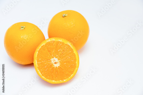 Two whole oranges and half of orange isolated on white background. Close-up side view. Citrus fruit and healthy food concept