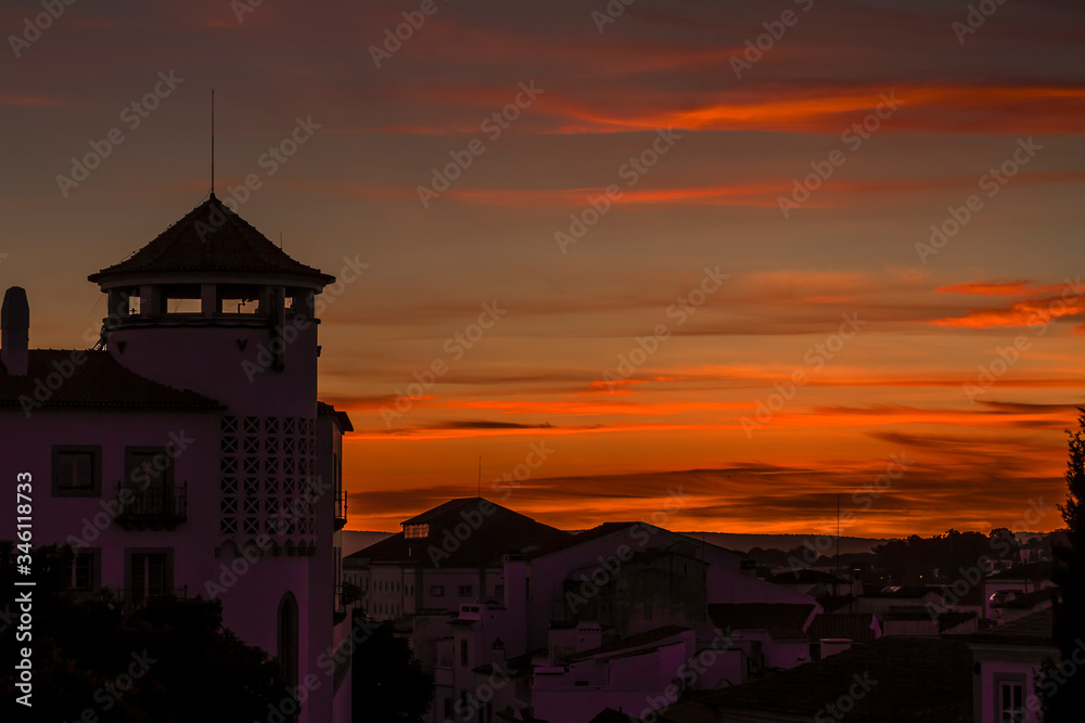 Fototapeta premium Bonita puesta de sol con nubes naranjas con una torre en el sur de Portugal