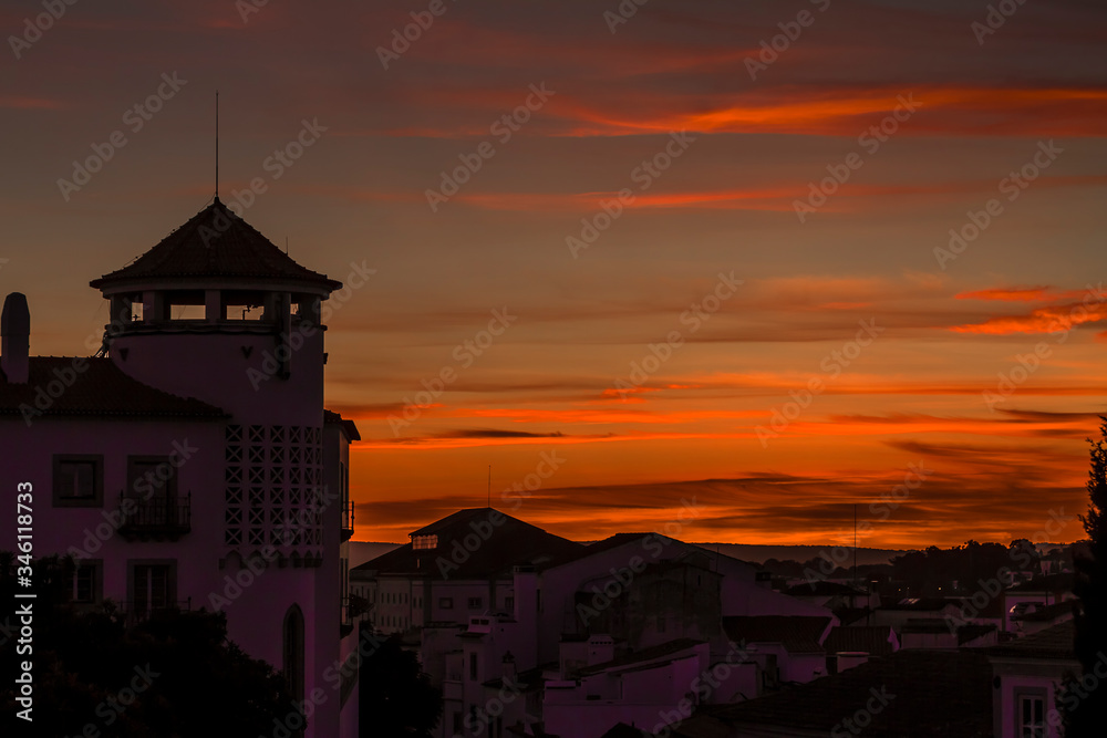 Bonita puesta de sol con nubes naranjas con una torre en el sur de Portugal
