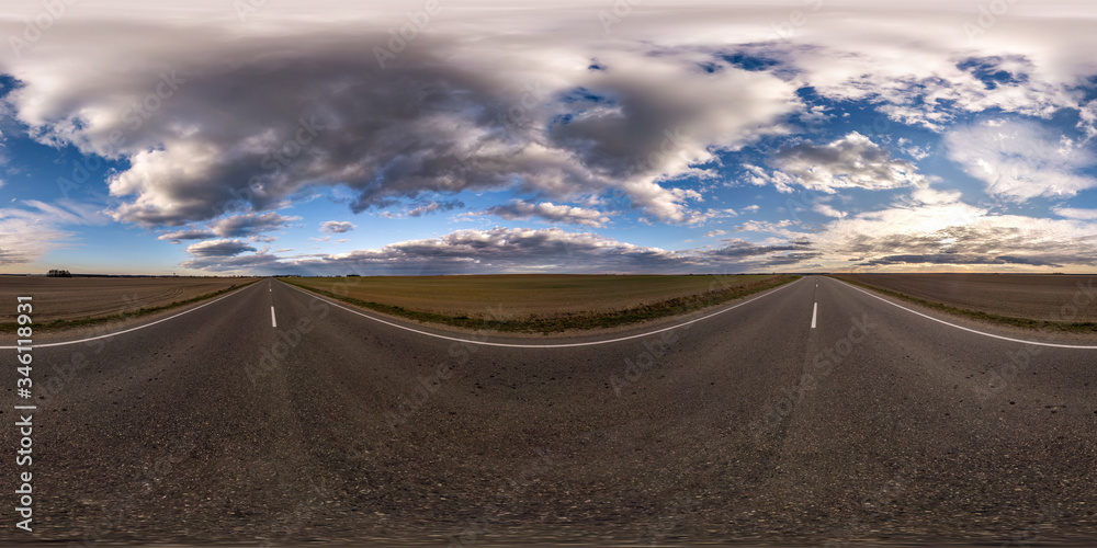 Full spherical seamless panorama 360 degrees angle view on no traffic asphalt road among fields in evening  before sunset with cloudy sky. 360 panorama in equirectangular projection, VR AR content