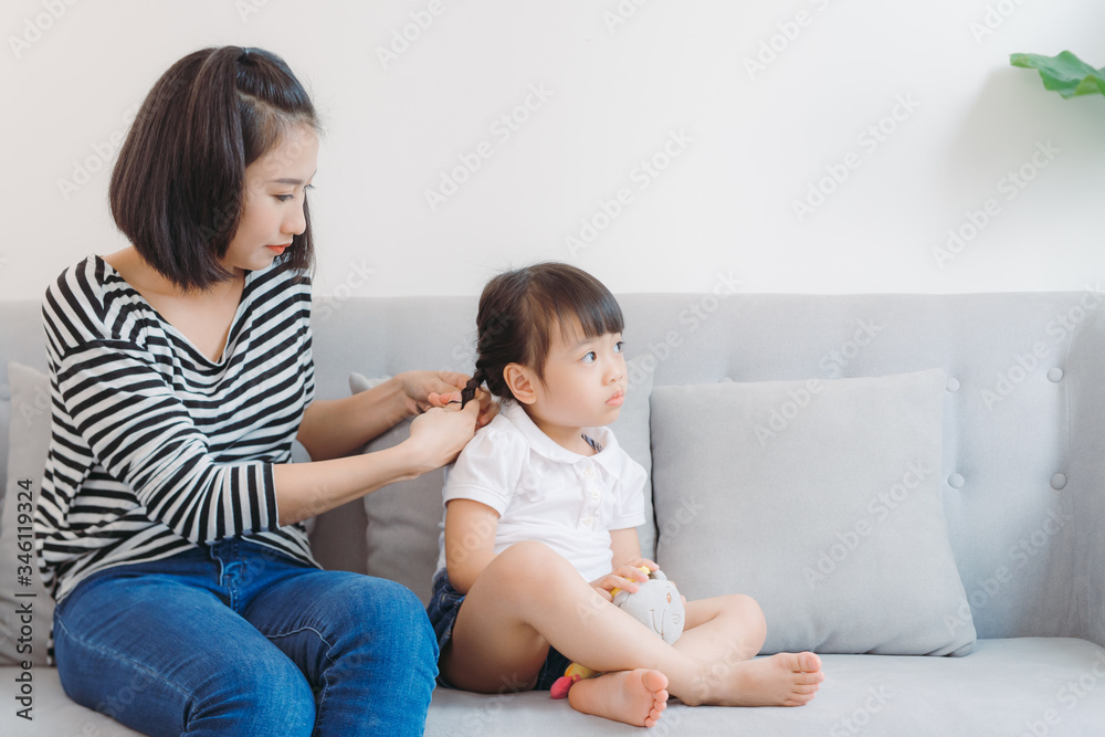 Mother doing styling hair braids for her little girl child. Mother doing styling hair braids for her little girl child.