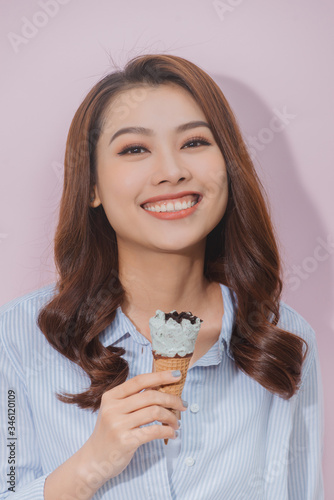 Young woman eats ice cream cone and looking at the camera