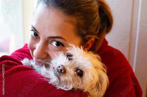ritratto di una ragazza chiara con gli occhi grandi e scuri vestita di rosso vicina al suo cane di razza maltese