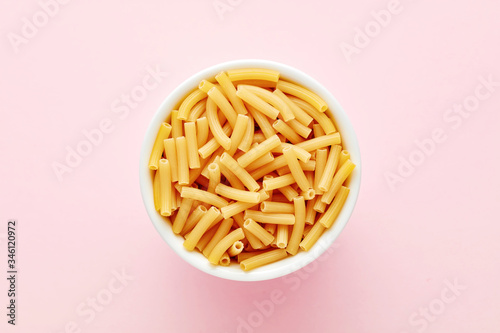 Heap of pipette rigate pasta in a white bowl on pink background photo