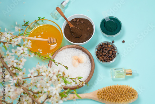Spa products for home body care for cellulite and acne. sea salt  coffee scrub  honey in plates on a blue background and a flower branch. spring composition of organic ingredients