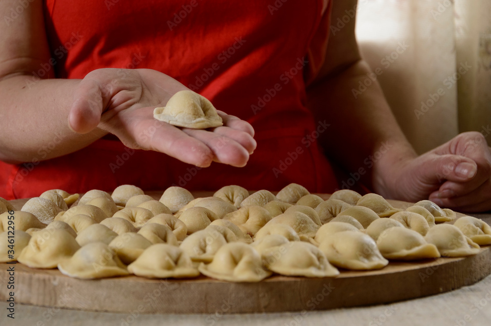 A woman makes dumplings and puts them on a cutting Board.