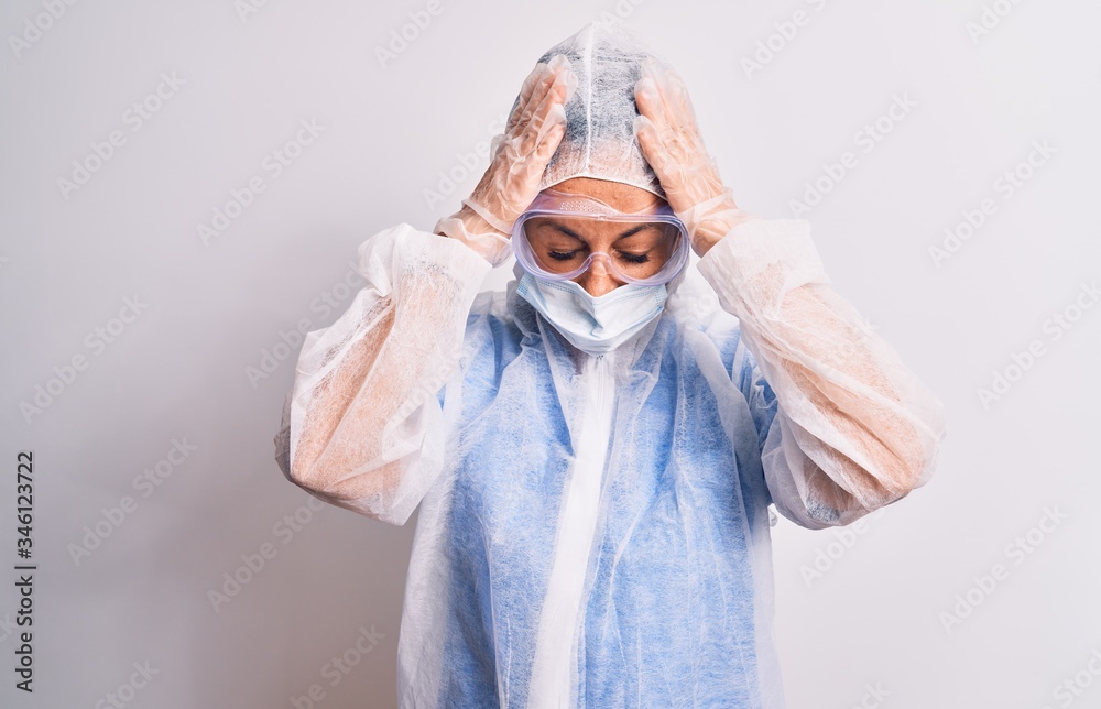 Middle age nurse woman wearing protection coronavirus equipment over white background suffering from headache desperate and stressed because pain and migraine. Hands on head. Middle age nurse woman wearing protection coronavirus equipment over white background suffering from headache desperate and stressed because pain and migraine. Hands on head.