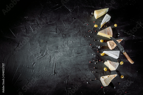 Different sorts of cheese. Сheese delicatessen on a black concrete background. Top view with copy space