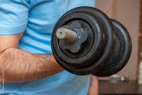 dumbbell in the man hand doing fitness sport exercise at home close up