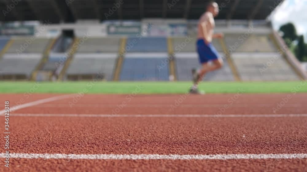 Young athletic man getting ready for marathon while running on stadium treadmill
