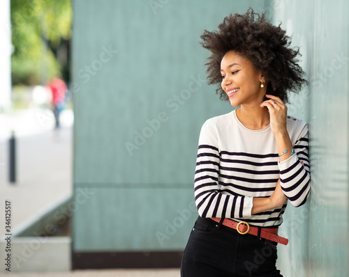 beautiful smiling young african american woman leaning against wall