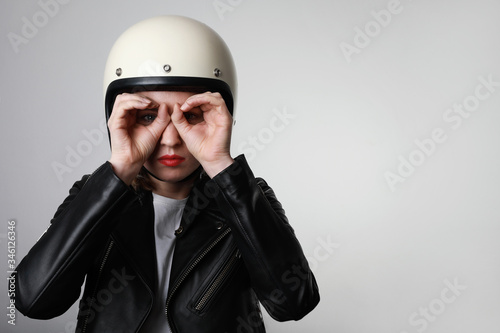 Young biker woman doing a hand gesture looking through binoculars. Free space for text. © face_reader_img