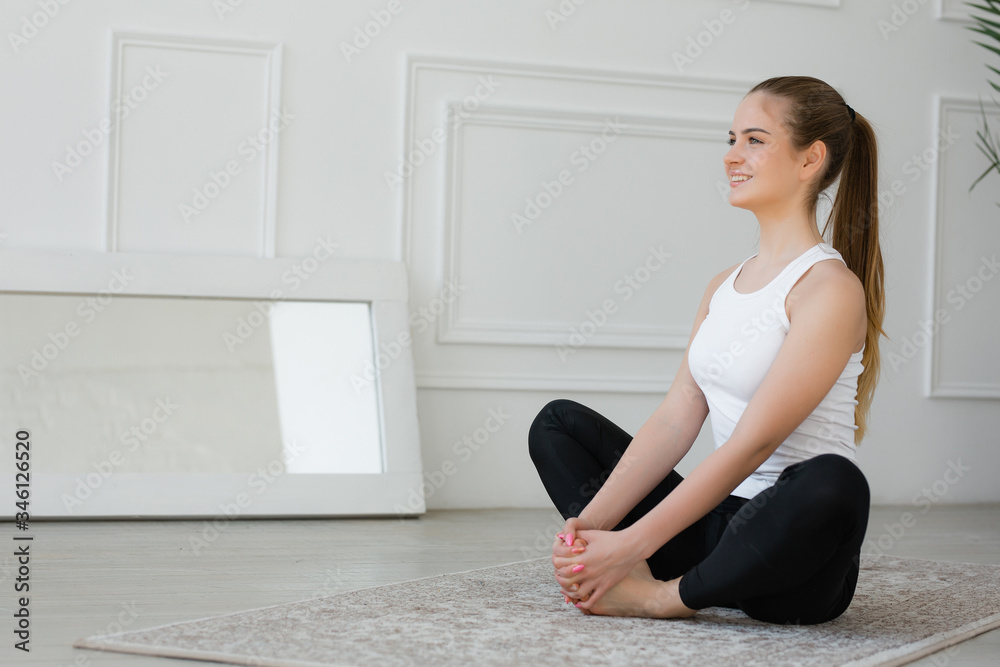 Athletic European woman sitting in a butterfly pose, doing exercises on the hip joints Athletic European woman sitting in a butterfly pose, doing exercises on the hip joints