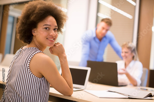 Young african american woman sitting and using laptop in a modern office