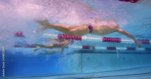 Three swimmers diving in pool underwater