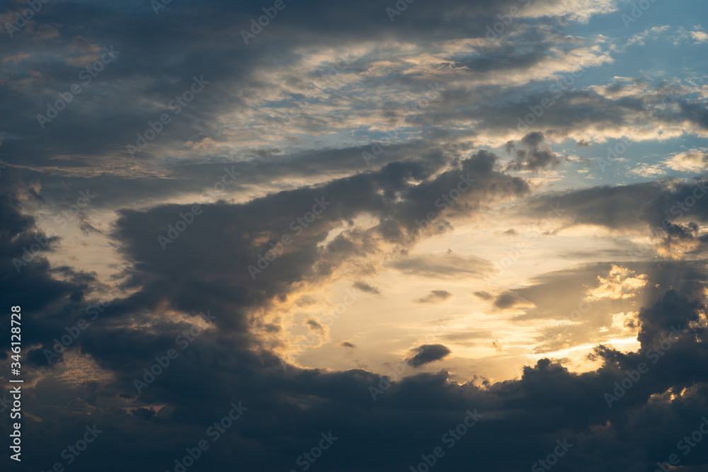 Obraz premium Blau-graue Wolkenberge hemmen dramatisch die Sicht auf den hellen Sonnenuntergang am Abend