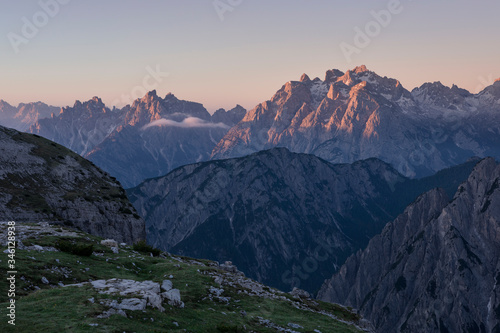Mountain landscape in the European Dolomite Alps underneath the Three Peaks with alpenglow during sunrise, layers of mountains, South Tyrol Italy.
