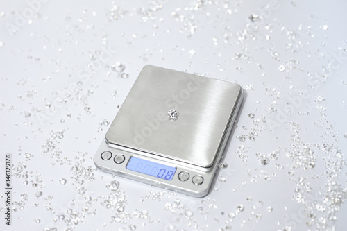Diamonds with weight scale on a white background. reflections on the ground. brilliant cut diamond held by tweezers, white gemstone. hold by hand, tester, magnifier , diamond checking equipment.
