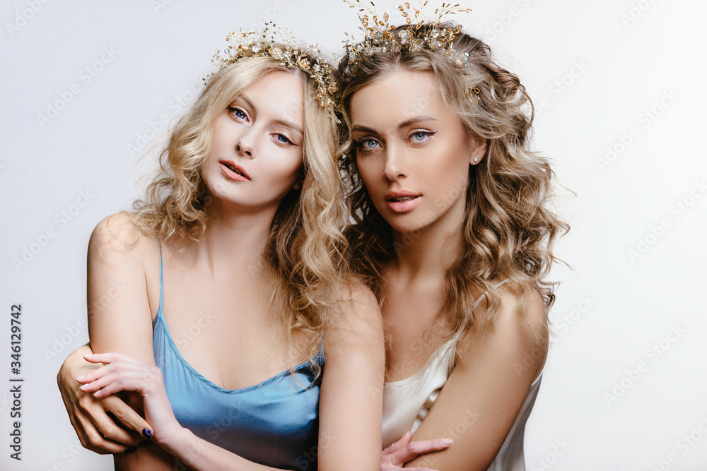 Two blue-eyed girls with hair jewelry. a pair of Young women in a hoop with stones and pearls. The concept of a wedding hairstyle and jewelry Two blue-eyed girls with hair jewelry. a pair of Young women in a hoop with stones and pearls. The concept of a wedding hairstyle and jewelry