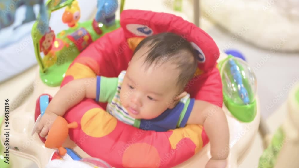 Funny asian 3 months baby playing in baby jumper,family concept.