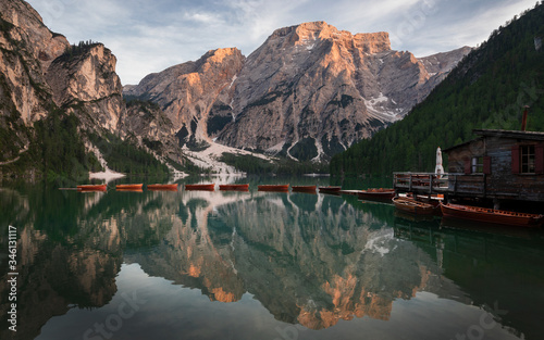Boat house with boats at Lake Prags during sunset in the Dolomite Alps, refelction of the mountains on the water surface, South Tyrol Italy. © Bastian Linder