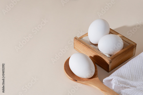 Chicken eggs in a wooden box on beige background with copy space, product with amino acids choline lecithin cholesterol calcium potassium phosphorus magnesium iodine protein vitamins healthy diet food photo