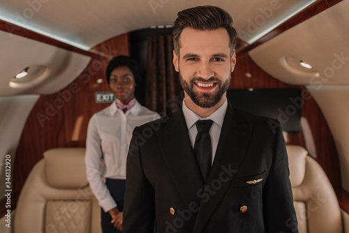 selective focus of handsome pilot smiling at camera near african american stewardess © LIGHTFIELD STUDIOS