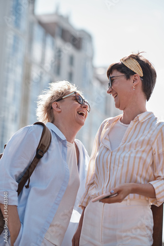 Two women laughing together while walking outdoor
