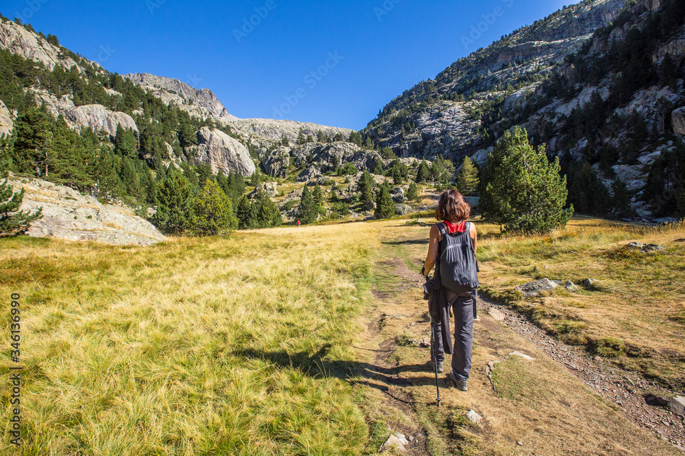A young woman walking in the valley going up from Baños de Panticosa in the Aragonese Pyrenees. Spain