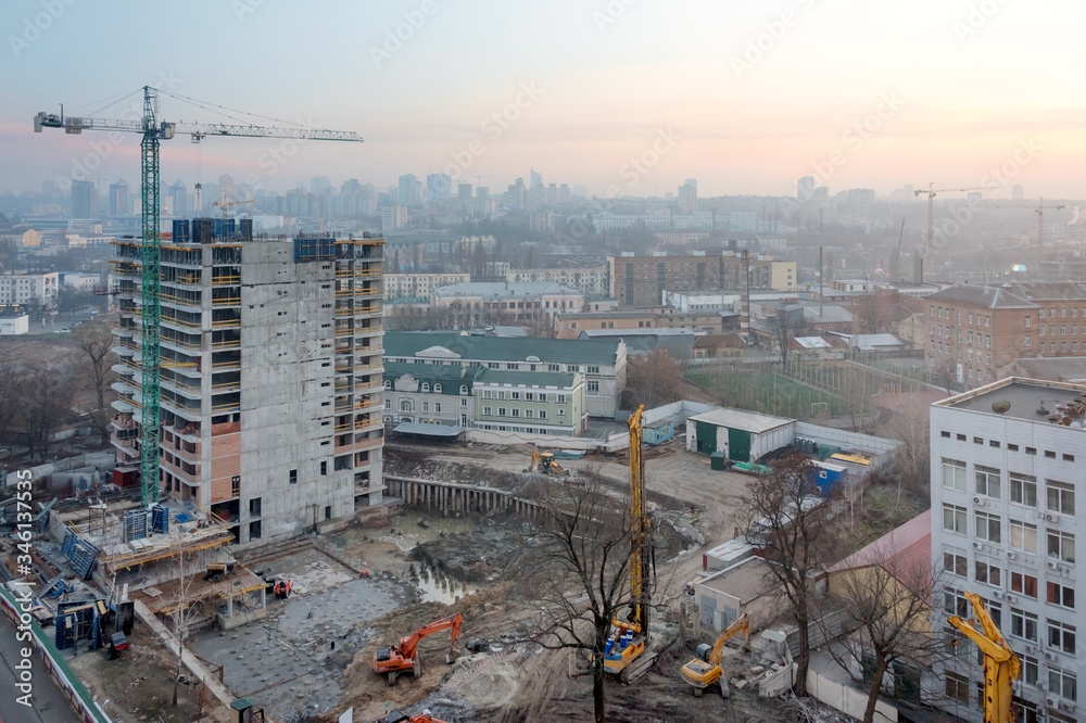 Building crane and buildings under construction against evening sky. Construction site, city at sunrise, Kyiv skyline