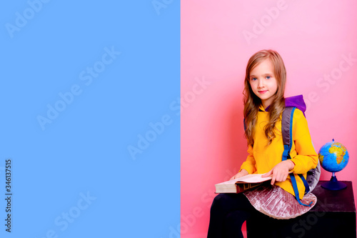 Back to school. Jump of a blonde schoolgirl with a backpack and a book. Pink Studio background. Education. Smiling at the camera. Copyspace. photo