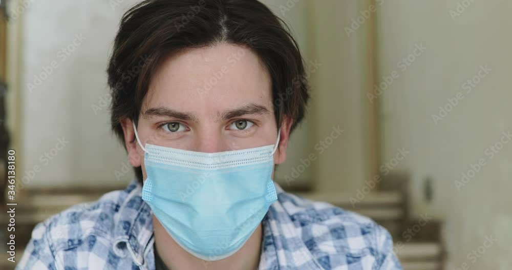 Close portrait of man in medical mask looking into camera indoor Close portrait of man in medical mask looking into camera indoor