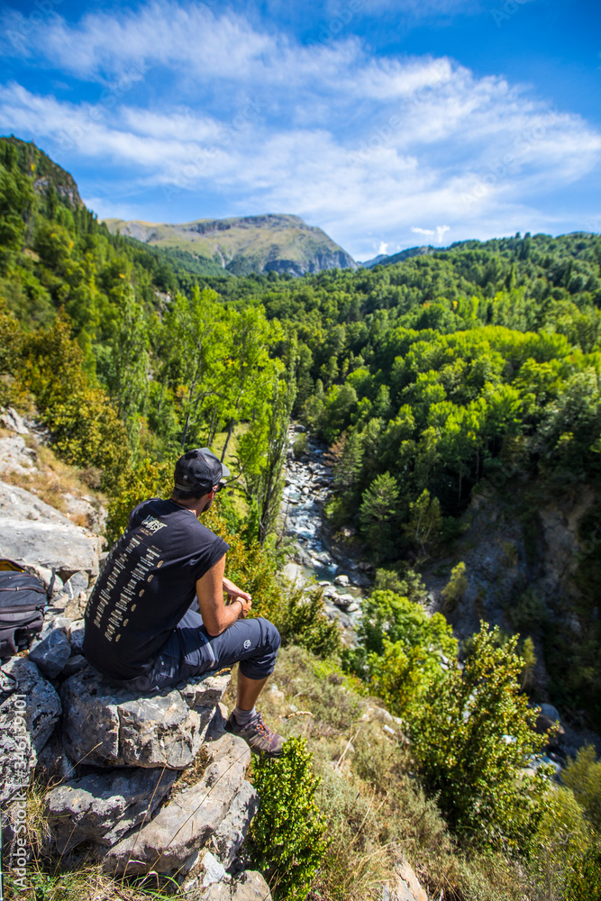 A young man looking at the Panticosa forest in the Pyrenees, Aragon. Spain